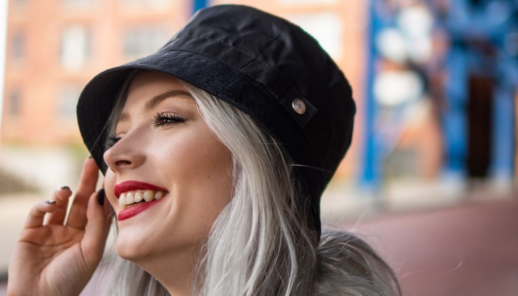 A woman in a black bucket hat smiling