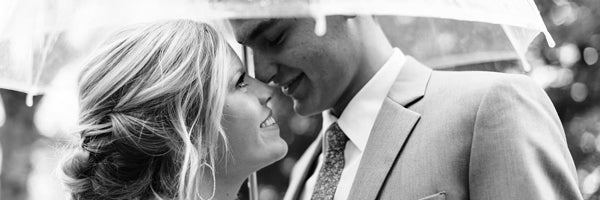 Black and White image of bride and groom underneath Signature Clear Bubble Umbrella