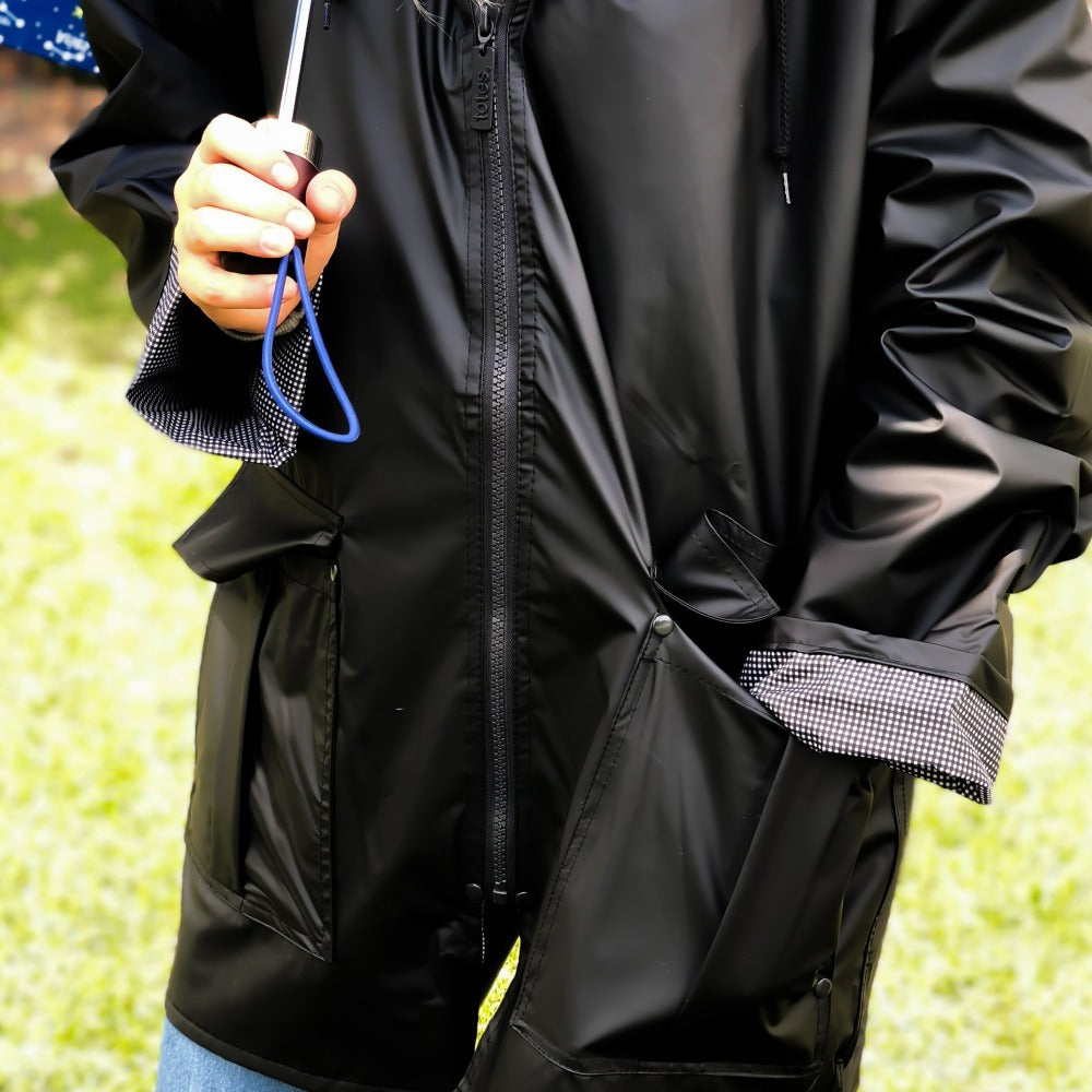 Woman wearing Lined Rain Slicker in black outside holding umbrella