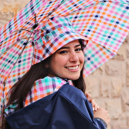 Woman holding Limited-Edition Auto Open Umbrella in rainbow gingham outside on brick wall