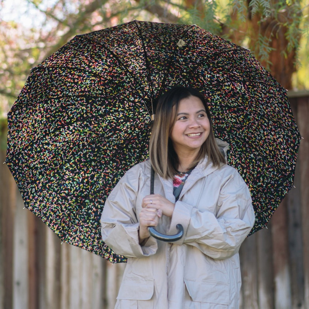 Woman holding 50th Anniversary Stick Umbrella in raindrop status front view outside on sunny day